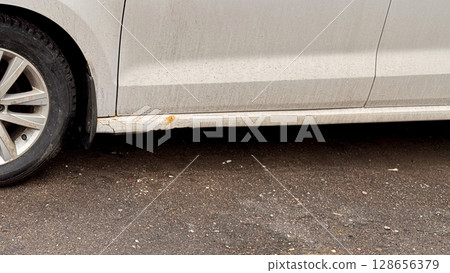An old car that is showing significant rust and wear, complete with a visibly damaged side panel, indicating neglect 128656379
