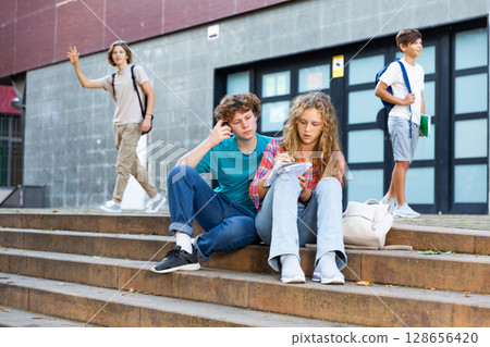 Teenagers preparing for exams on stairs in campus Teenagers preparing for exams on stairs in campus 128656420