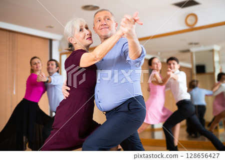 Senior couple dancing slow ballroom dance in choreography studio Senior couple dancing slow ballroom dance in choreography studio 128656427