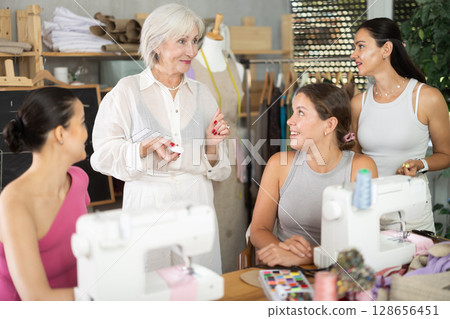 Female dressmaker explaining pattern modeling on chalkboard during course for women 128656451