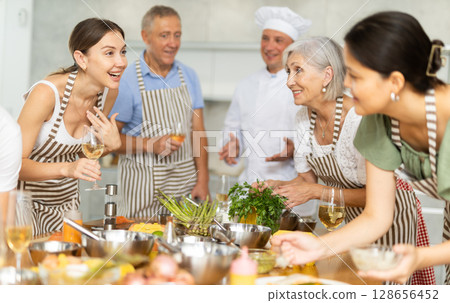 Cheerful woman drinking wine and talking during group culinary masterclass Cheerful woman drinking wine and talking during group culinary masterclass 128656452