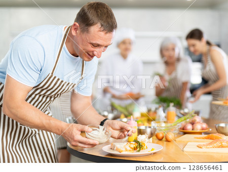 Adult man pouring sauce into dish at master class 128656461