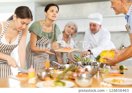 Young guy cook teaches to cook group of people 128656463