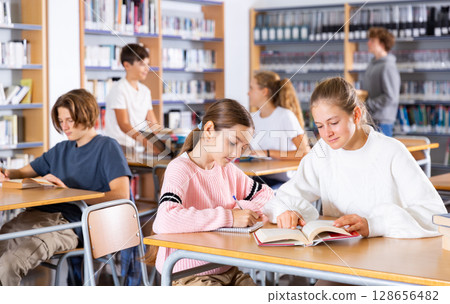 Group of girls and boys preparing for exams in library 128656482