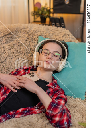 Woman listening to audiobook with wireless headphones at home, nodding with interest full attention Woman listening to audiobook with wireless headphones at home, nodding with interest full attention 128656527