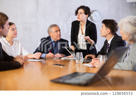 Female director gives instructions to managers in deliberation room 128656553