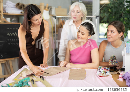 Adult woman teacher explains to group how to make pattern Adult woman teacher explains to group how to make pattern 128656585