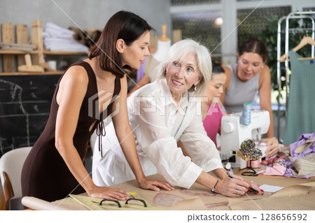Elderly female teacher explains to group how to draw pattern Elderly female teacher explains to group how to draw pattern 128656592