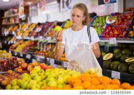 Focused fifteen-year-old girl chooses ripe apples 128656594