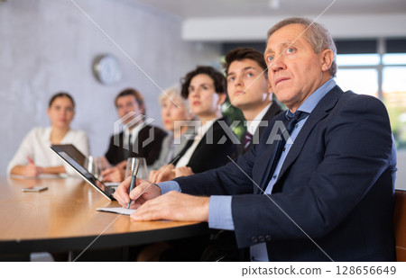 Group of businessmen attentively watching a presentation in meeting room 128656649