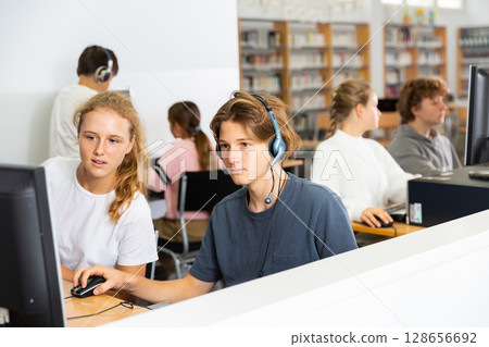 Portrait of a fifteen-year-old schoolboy in headphones at a computer Portrait of a fifteen-year-old schoolboy in headphones at a computer 128656692