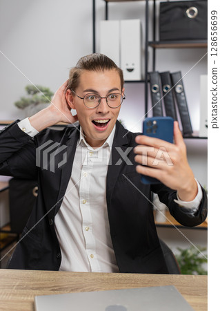 Happy amazed young Caucasian businessman working on smartphone shocked by sudden victory at home 128656699