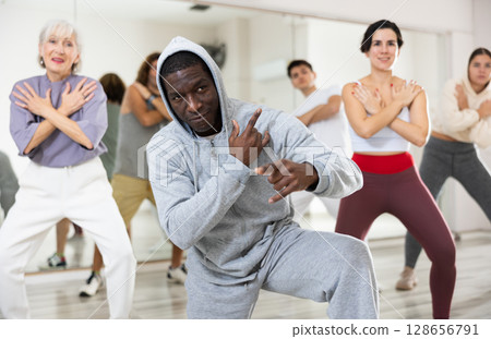 Happy african man learning new hip-hop dance in group dance lesson 128656791