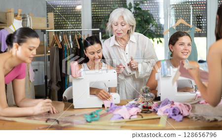 Group of busy women sewing and drawing with teacher at dressmaking courses Group of busy women sewing and drawing with teacher at dressmaking courses 128656796