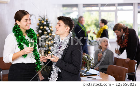 Young couple flirting with each other while celebrating christmas in modern office Young couple flirting with each other while celebrating christmas in modern office 128656822