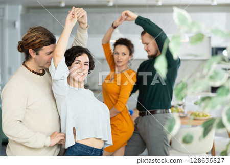 Friends dancing. Cheerful young people dancing and drinking while enjoying home party on room Friends dancing. Cheerful young people dancing and drinking while enjoying home party on room 128656827