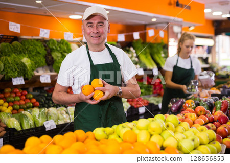 Portrait of a confident salesman holding oranges in his hands Portrait of a confident salesman holding oranges in his hands 128656853