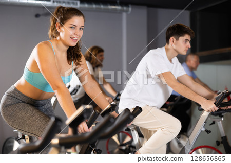 Young girl doing cardio workout on exercise bike in gym 128656865