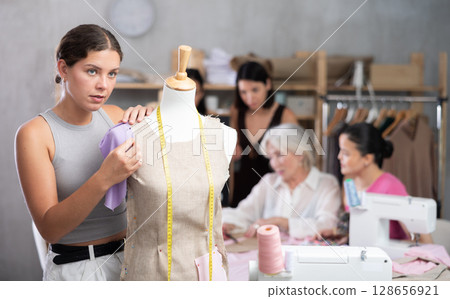 Young woman working with mannequin in workshop 128656921