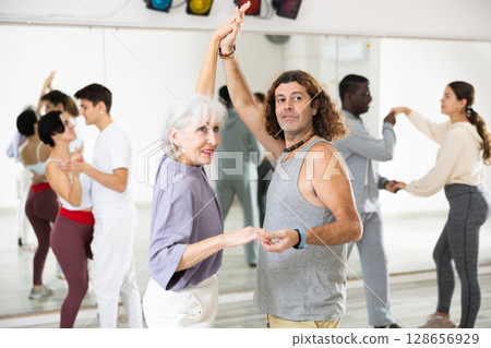 Caucasian man and mature woman rehearsing latin paired dance moves 128656929