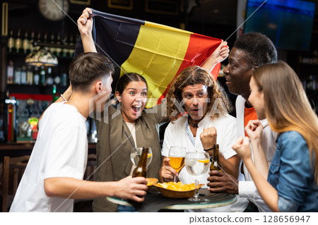 Group of football fans cheering for favorite Belgian team in sports bar Group of football fans cheering for favorite Belgian team in sports bar 128656947