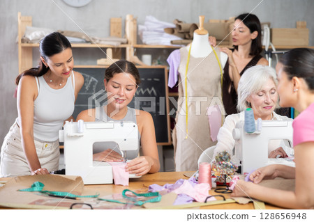 Group of happy attendees of dressmaking courses engaged in different activities 128656948