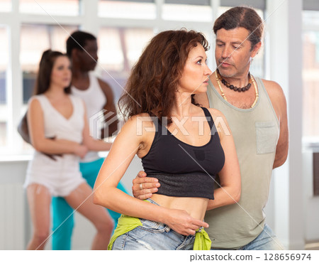 Woman and man dancing sensual bachata during group class 128656974