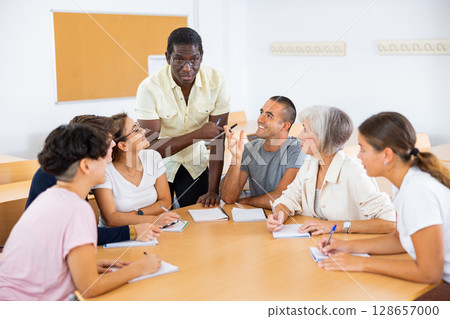 Friendly African American English tutor giving language courses to group of adults 128657000