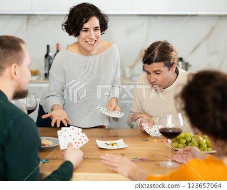 Happy group of friends playing poker cards and drinking wine 128657064