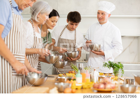 Professional chef imparting cooking skills to group at culinary courses Professional chef imparting cooking skills to group at culinary courses 128657066