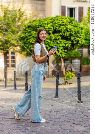 Tourist young woman using smartphone looking for search a way on map in navigator app outdoors 128657258