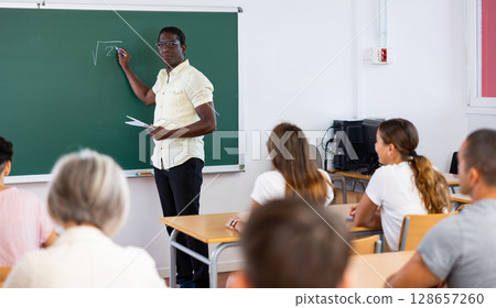 Male teacher explaining subject to students in classroom 128657260