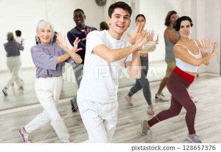 Smiling guy learning dynamic dances in group choreography class 128657376