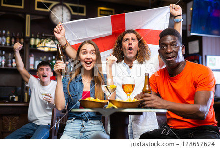 Group of football fans rooting for England team in sports bar Group of football fans rooting for England team in sports bar 128657624