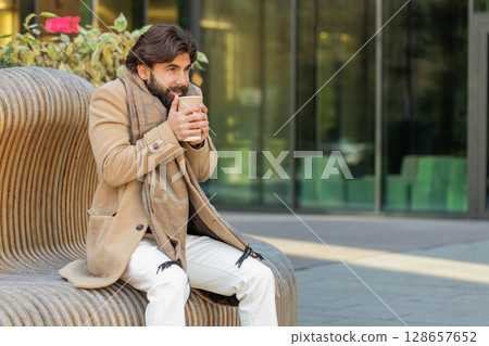 Indian young businessman tourist enjoying drinking morning warming hot takeout coffee, tea beverage 128657652