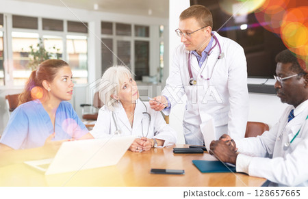 Male doctor speaks at meeting of colleagues and tells reports on condition of patients. Male doctor speaks at meeting of colleagues and tells reports on condition of patients. 128657665