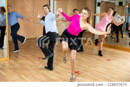 Cheerful man and woman practicing ballroom dances in ballroom 128657673