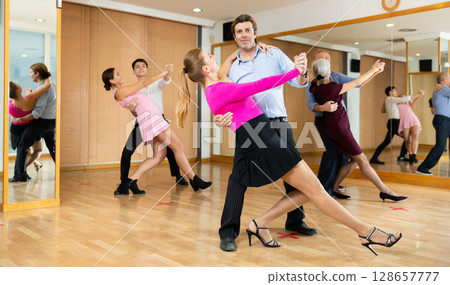 Couple of dancers rehearsing ballroom dances in dance studio Couple of dancers rehearsing ballroom dances in dance studio 128657777