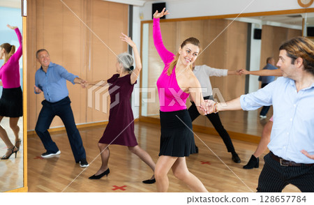 Couple of dancers rehearsing ballroom dances in dance studio Couple of dancers rehearsing ballroom dances in dance studio 128657784