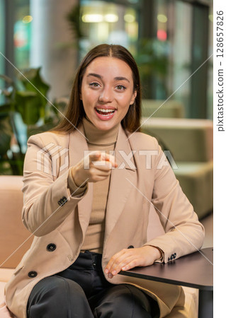 Portrait of Caucasian young businesswoman pointing to camera selecting hire sitting in office lobby 128657826