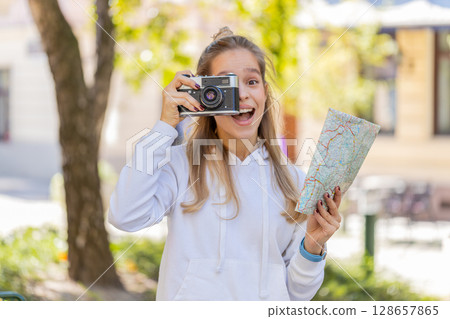 Caucasian young woman tourist looking at city map, making photo pictures on retro vintage camera 128657865