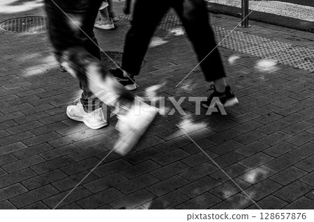 Urban Steps - People Walking on Sunlit Pavement 128657876