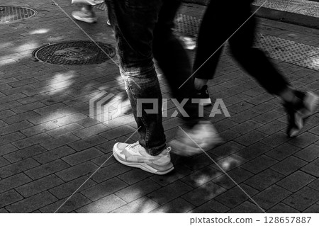 Urban Steps - People Walking on Sunlit Pavement Urban Steps - People Walking on Sunlit Pavement 128657887