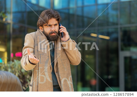 Indian young businessman tourist arguing talking on smartphone while walking in downtown city street 128657894