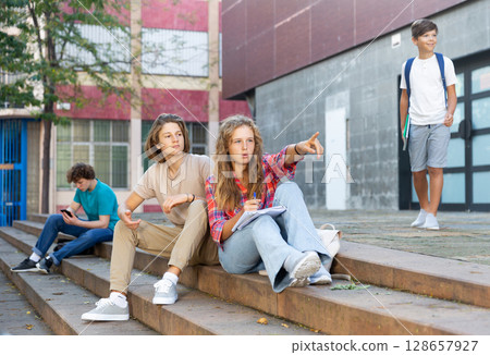 Teenagers sitting on stairs beside school 128657927