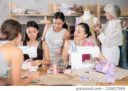 Group of women enjoying teamwork during hands-on dressmaking class Group of women enjoying teamwork during hands-on dressmaking class 128657969