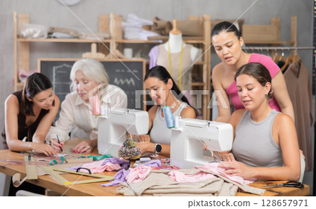 Group of women sew and draw pattern at sewing workshop Group of women sew and draw pattern at sewing workshop 128657971