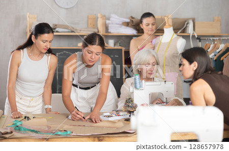 Group of women sew, draw pattern and work with mannequin 128657978