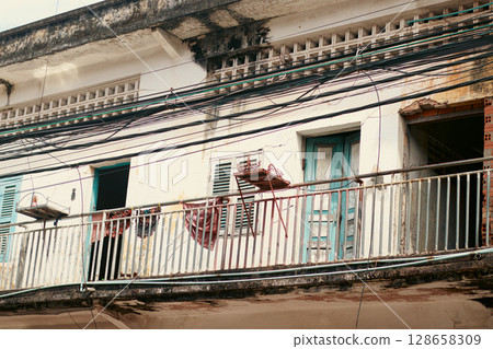 An old colonial building's balcony with multiple wires overhead, Kampot Cambodia 128658309