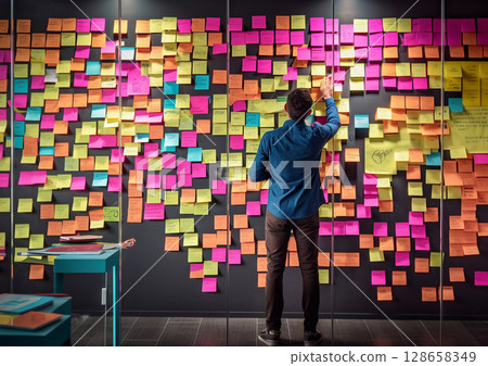 Office worker putting sticky notes on wall, having new idea or business plan.Rear view.AI Generative 128658349